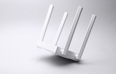 Modern white four-antenna wireless Wi-Fi router floating on gray background.
