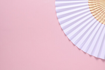 Traditional white Asian hand fan on pink background. Copy space