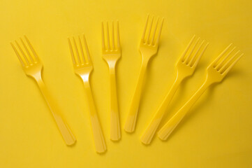 Set of plastic forks on yellow background