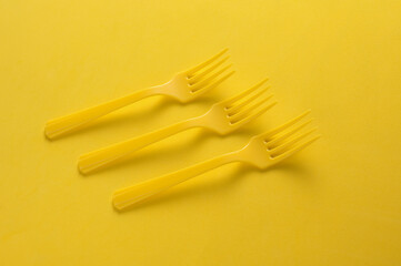 Set of plastic forks on yellow background