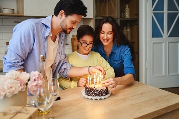 Family celebrates a birthday together while lighting candles on a cake