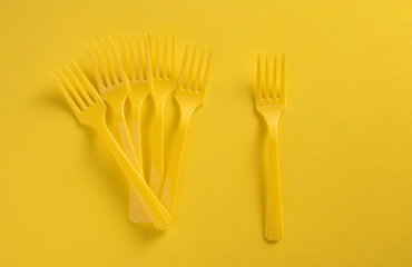 Set of plastic forks on yellow background