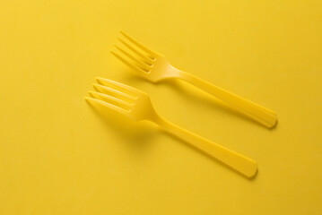 Set of plastic forks on yellow background