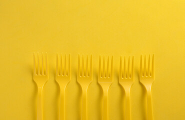 Set of plastic forks on yellow background