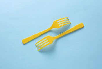 Yellow Plastic forks on blue background. Top view