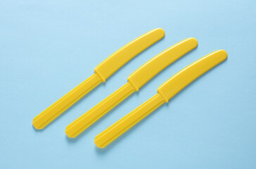 Yellow Plastic knives on blue background
