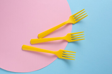 Yellow Plastic forks on blue pink background. Creative layout