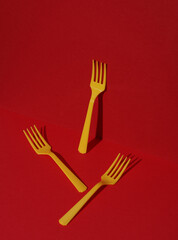 Yellow Plastic forks on red background with shadow. Minimalism. Creative layout. Food concept