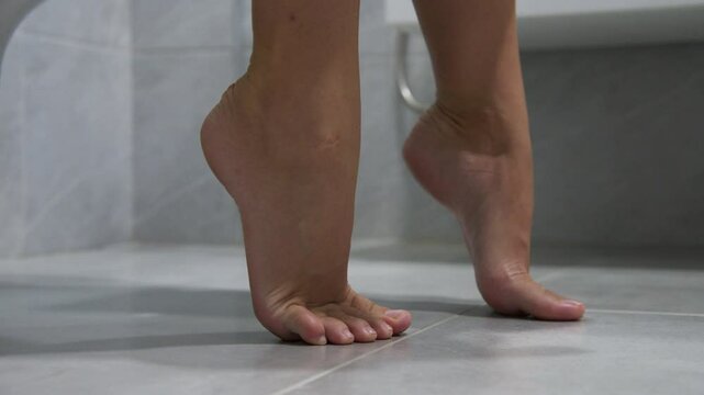 Sweet routine. Woman sitting on toilet in home bathroom taking off denim shorts. Close-up of feet. Concept of women's health and virginity.