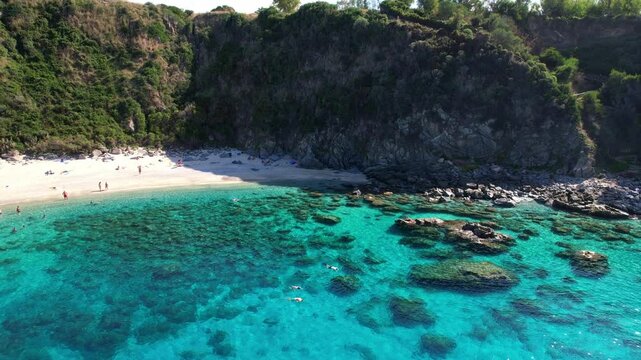 4K Aerial drone video of one of the most beautiful beaches in the world with turquoise clear blue water and white sand with big rocks on a sunny summer day. Marinella di Zambrone Paradiso Tropea Italy