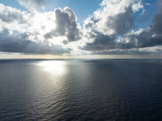 Early morning sunlight peeks through drifting clouds over the Pacific Ocean.