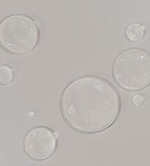 Close-up of clear liquid droplets neutral cosmetic background. Hydration concept, skincare serum and moisture-rich beauty product