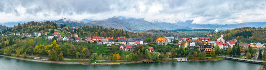 Obraz premium Croatia, Fuzine. Panorama view of a line of bright houses on a mountain slope near the shore of a lake in autumn. Picturesque village 