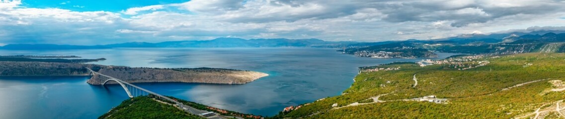 Aerial panorama view of Adriatic Sea, Krk Bridge, Krk island, mountains in the distance. Croatia travel 
