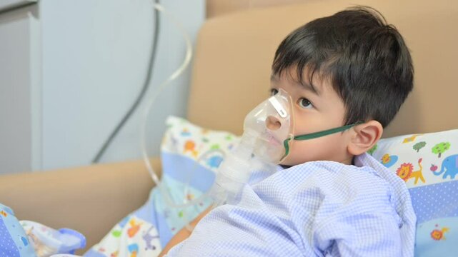Boy 4 years old , inhale medication by inhalation mask to cure Respiratory Syncytial Virus (RSV) on hospital bed. Admitted patient boy inhalation therapy.