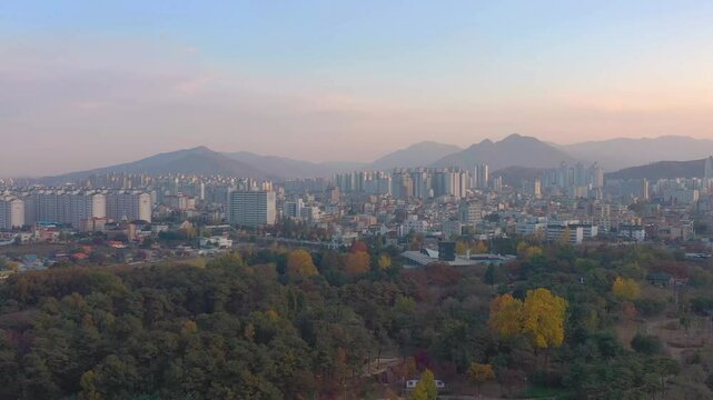 ASAN, SOUTH KOREA - OCTOBER 15, 2024: Stunning aerial view showcasing the vibrant cityscape alongside picturesque mountains during sunset