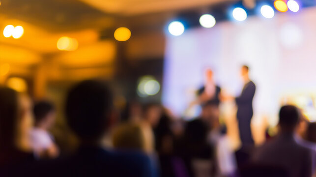 Conference panel discussion with a blurred audience, focusing on speakers and stage lighting during a corporate event.