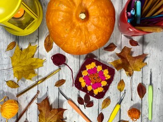 Autumn composition with crocheting, pumpkin, leaves, scissors and clews and hooks fall vibe cozy...