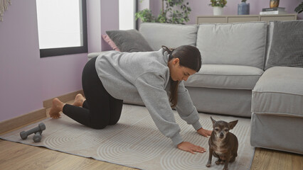 A young adult woman pets her chihuahua at home, hinting at a cozy indoor workout scene.