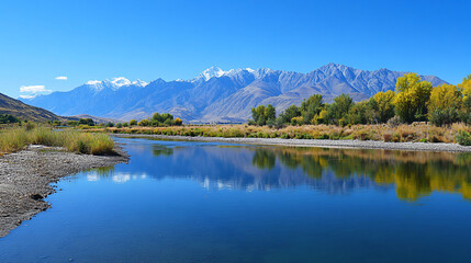 Fototapeta premium A riverbank with a picturesque view of mountains in the background, reflecting in the water.
