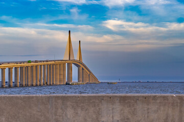 Obraz premium A serene waterscape features the long Sunshine Skyway bridge from Pinellas Point Park St Petersburg Florida The bridge stretching across a calm blue expanse, with wispy clouds scattered across the sky