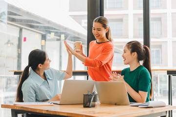 Collaborative women in modern office share ideas and celebrate success while enjoying coffee. Their expressions reflect teamwork and positivity in bright workspace