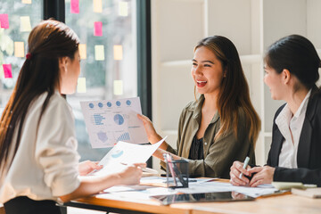 group of three women engaged in business meeting, discussing charts and graphs with enthusiasm. setting is bright and modern, reflecting collaborative atmosphere