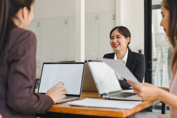 group of professional women engaged in meeting, discussing ideas and collaborating with laptops and documents on table. Their expressions reflect positivity and teamwork