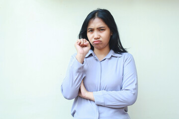 displeased offended asian young woman employee crying with fist pump and folded arm looking to camera sadly wear formal purple shirt standing over isolated white background