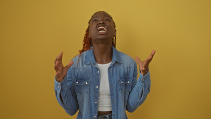 Anguished young african woman in denim jacket over yellow background expressing desperation