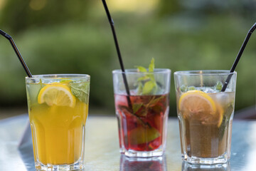 Three drinks with straws in them are on a table