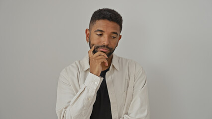 Thoughtful young african american man with beard wearing casual shirt over isolated white background