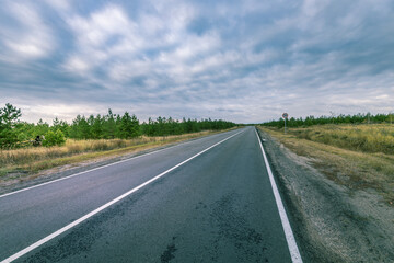 A long, empty road with a few trees in the background