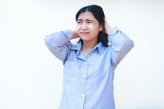 stress asian woman wearing blue striped shirt holding her hair with frowing face standing over isolated white background, look away