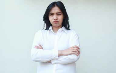 studio shot of sad gloomy asian woman boss frowning face angry look at camera with crossed arm wear white formal shirt standing over isolated background