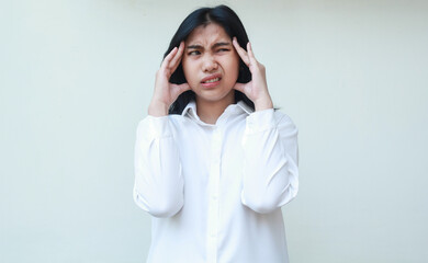 studio shot of stressed asian young business woman executive feeling dizzy holding her head with...