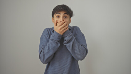 Surprised young man with beard in casual blue sweater over isolated white background, covering...