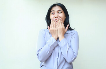 surprised asian young business woman covering her open mouth looking away to empty space wearing purple formal shirt standing over isolated white background