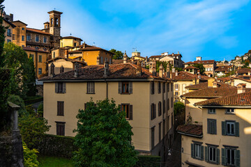 View of beautiful old buildings in old town of Bergamo in Italy against blue sky on sunny day. Lombardy. Sightseeing of old european city. Postcard.