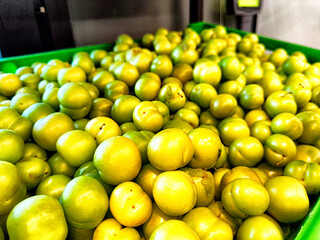 Fresh green plums piled high in a vibrant crate at a local market during the summer harvest season