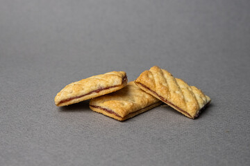 three rectangular jam-filled cookies stacked in a pile on a gray background
