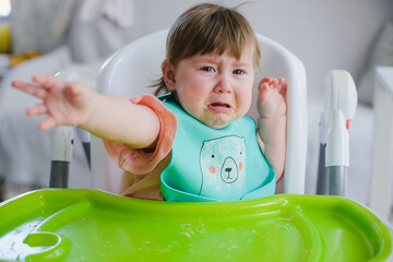 A small child is crying at the table. He doesn't want to eat