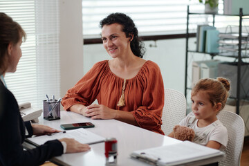Young mother with child having consultation with social worker in social service