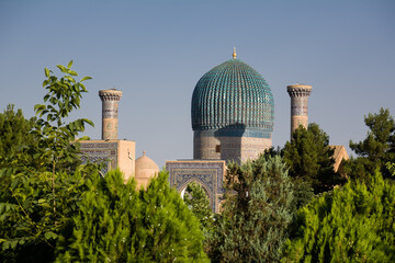 Portal and Dome of the Gur Amir Mausoleum surrounded by greenery in Samarkand - Uzbekistan