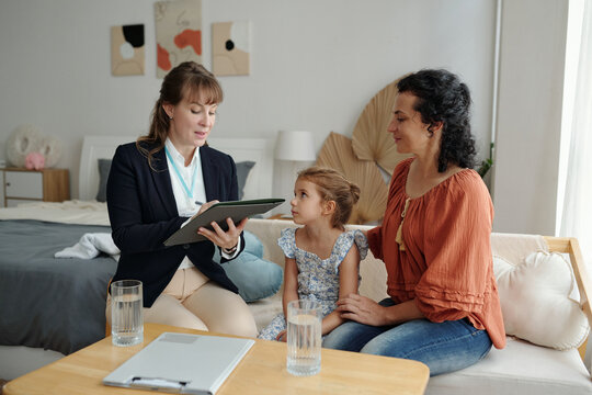 Social worker talking to adoptive family and making notes in document during her visit to home