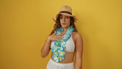 Woman wearing floral lei and sun hat standing against yellow wall