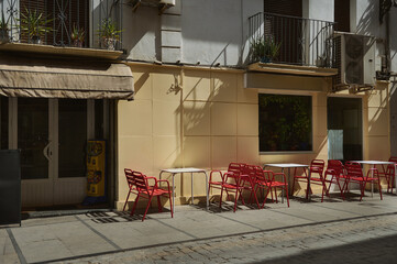 Outdoor cafe seating with red chairs under sunlight