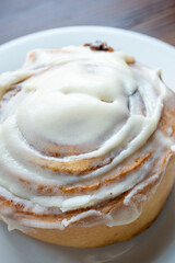 Cinnamon roll on a plate on a wooden background with a glass of espresso next to it
