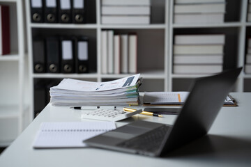 Office Desk Chaos: A cluttered office desk with a stack of papers, a laptop, a calculator, a pen,...
