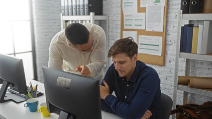 Boss scolding employee in office with two men while one sits at desk and another stands over him, surrounded by computers, papers, and bookshelves in a professional environment.